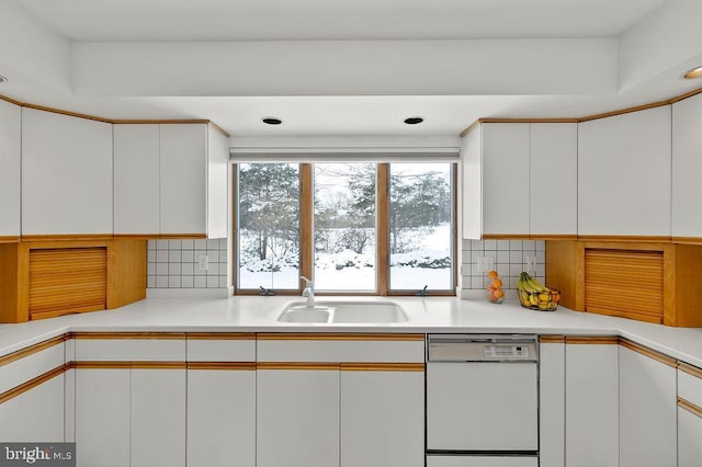 kitchen with white dishwasher, sink, and white cabinets