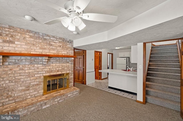 unfurnished living room with a brick fireplace, light colored carpet, a textured ceiling, and ceiling fan