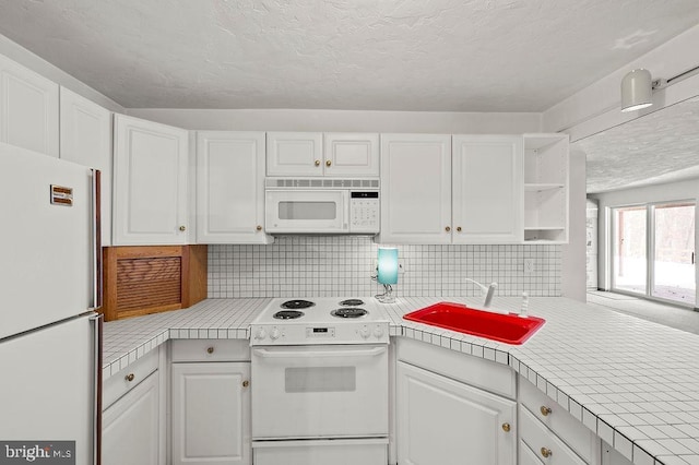 kitchen with tile countertops, tasteful backsplash, white cabinetry, sink, and white appliances