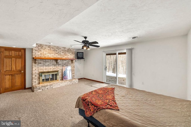 carpeted bedroom with a brick fireplace, a textured ceiling, access to outside, and ceiling fan