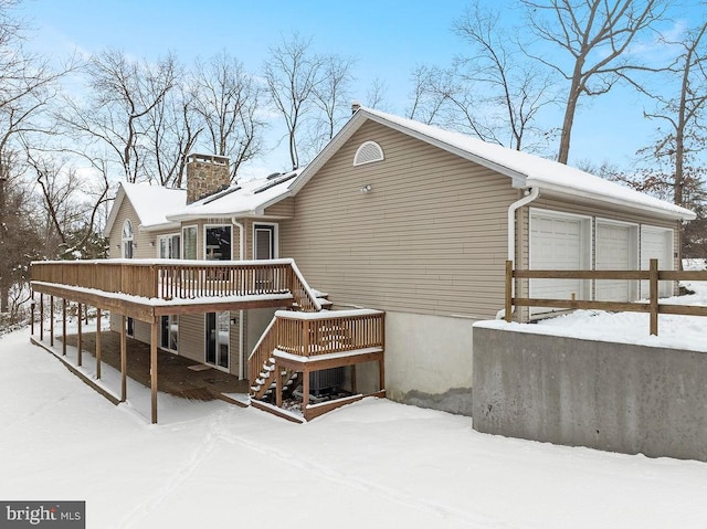 snow covered back of property with a deck