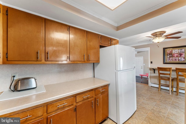 kitchen with tasteful backsplash, white fridge, ceiling fan, a tray ceiling, and crown molding