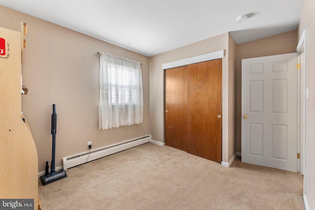 unfurnished bedroom featuring a baseboard radiator, light colored carpet, and a closet