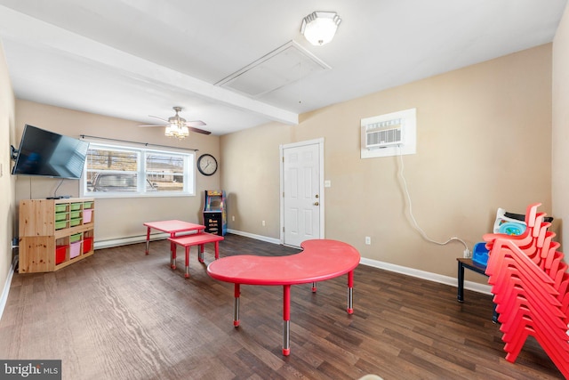 recreation room with a wall mounted AC, dark hardwood / wood-style flooring, beamed ceiling, ceiling fan, and a baseboard heating unit