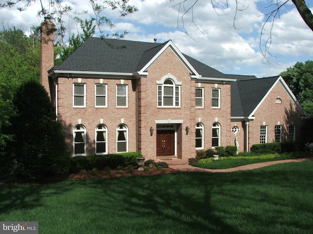 colonial-style house featuring a front lawn