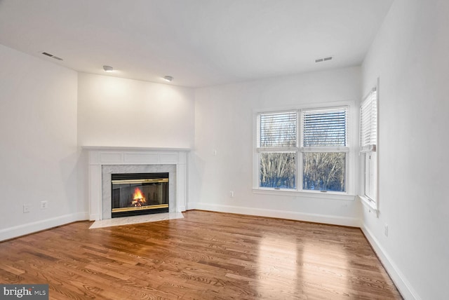 unfurnished living room featuring a high end fireplace and hardwood / wood-style floors