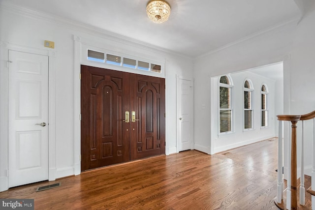 foyer entrance featuring hardwood / wood-style flooring, plenty of natural light, and crown molding