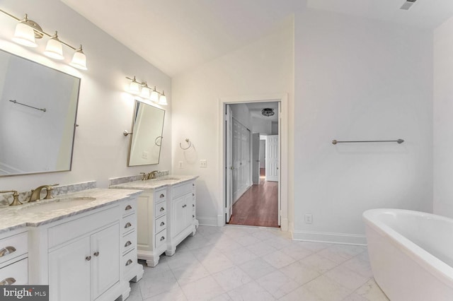 bathroom with vanity, vaulted ceiling, and a tub