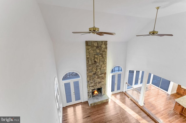 living room featuring a stone fireplace, high vaulted ceiling, ceiling fan, and hardwood / wood-style flooring