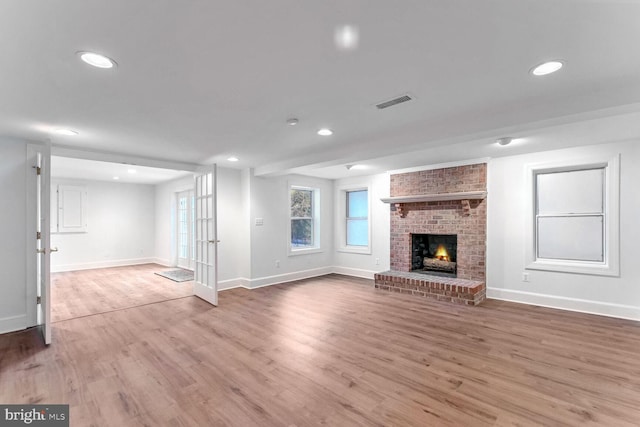 unfurnished living room featuring hardwood / wood-style floors and a brick fireplace