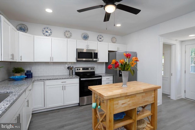 kitchen with white cabinetry, light stone countertops, backsplash, and stainless steel appliances