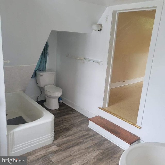 bathroom featuring wood-type flooring, toilet, and a bathing tub