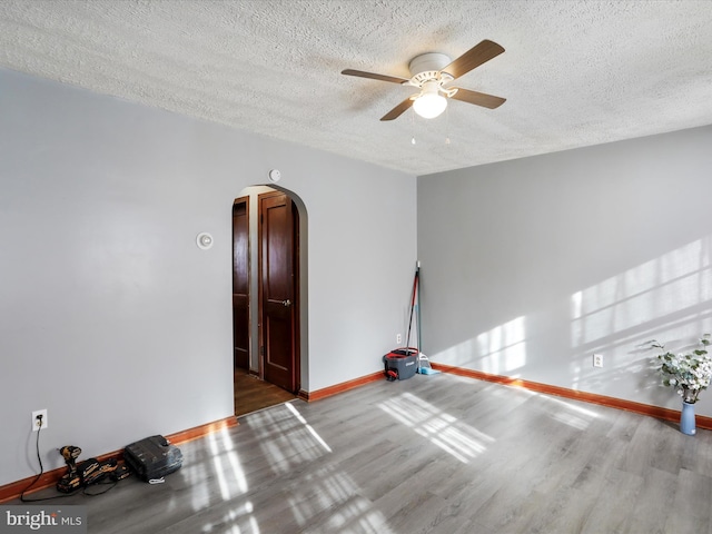 spare room with ceiling fan, wood-type flooring, and a textured ceiling