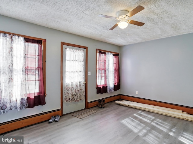 foyer featuring baseboard heating, ceiling fan, light hardwood / wood-style floors, and a textured ceiling