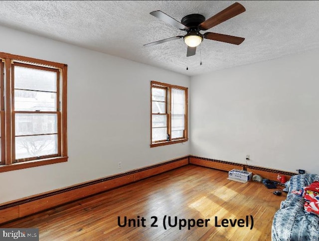 spare room featuring ceiling fan, a baseboard radiator, hardwood / wood-style floors, and a textured ceiling