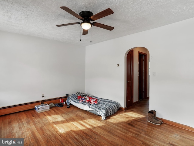 bedroom featuring hardwood / wood-style flooring, ceiling fan, and a textured ceiling