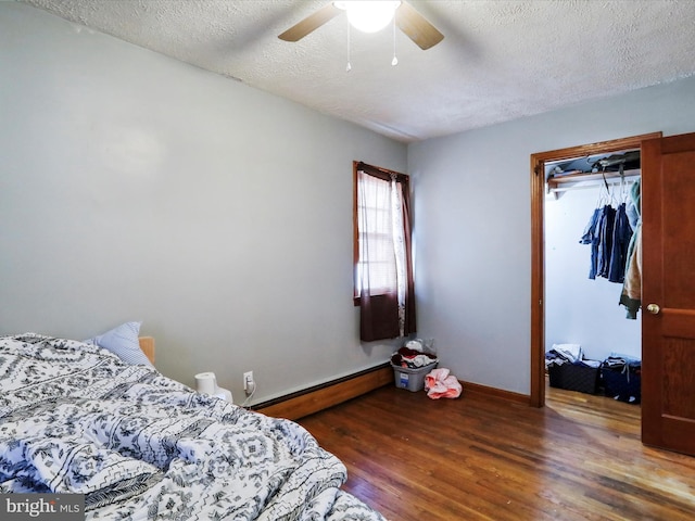 bedroom with dark hardwood / wood-style flooring, a textured ceiling, ceiling fan, and baseboard heating