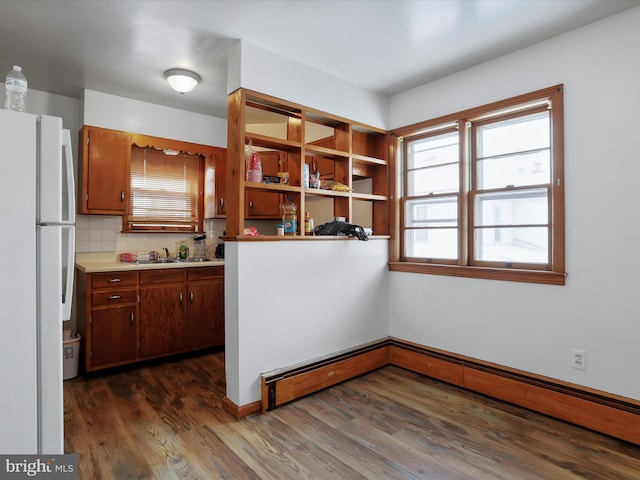 kitchen featuring tasteful backsplash, dark hardwood / wood-style flooring, a baseboard radiator, kitchen peninsula, and white fridge