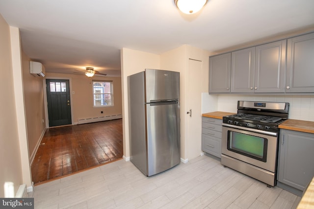 kitchen with butcher block counters, gray cabinetry, a wall mounted AC, and appliances with stainless steel finishes