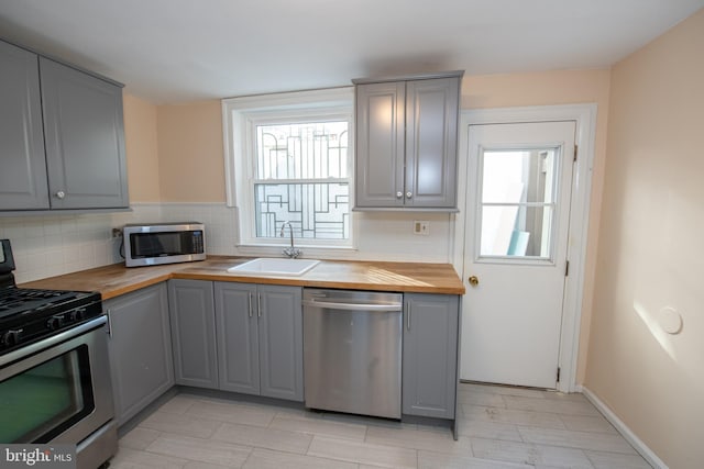 kitchen featuring butcher block counters, sink, tasteful backsplash, and stainless steel appliances