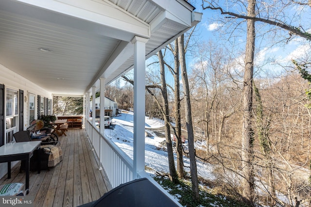 snow covered deck featuring covered porch