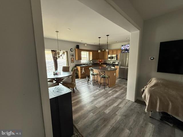 interior space with a breakfast bar area, a center island, dark hardwood / wood-style flooring, a notable chandelier, and stainless steel appliances