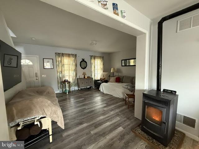 bedroom featuring dark hardwood / wood-style flooring and a wood stove