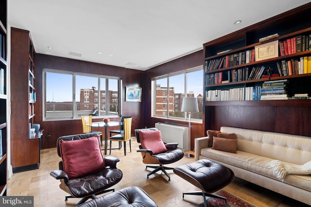 sitting room featuring light parquet flooring, a healthy amount of sunlight, and wood walls