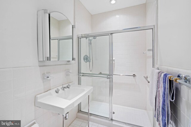 bathroom featuring tile patterned floors, an enclosed shower, and tile walls