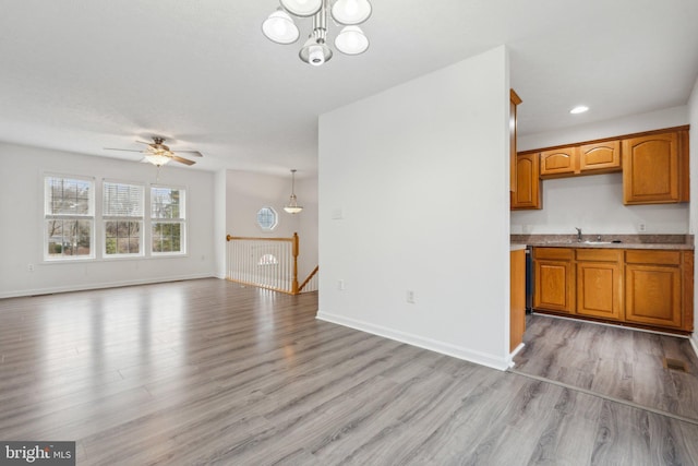 kitchen with pendant lighting, ceiling fan with notable chandelier, and light hardwood / wood-style flooring