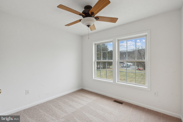 carpeted spare room featuring ceiling fan and plenty of natural light