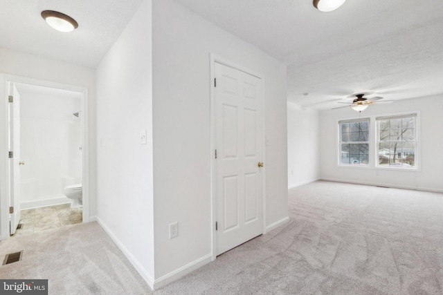 hall featuring light colored carpet and a textured ceiling