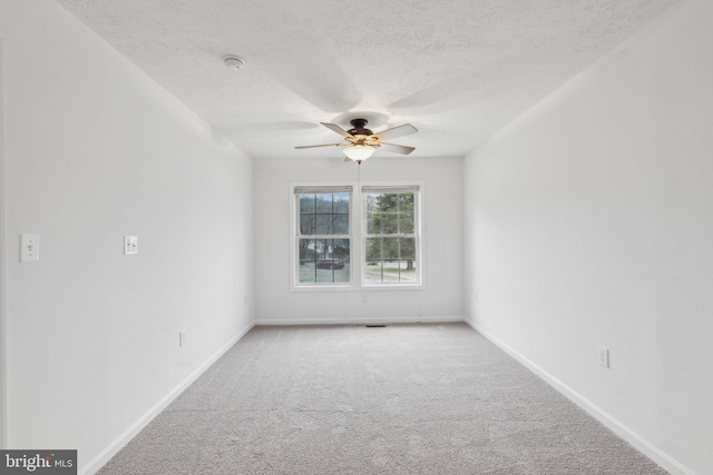 carpeted spare room featuring a textured ceiling and ceiling fan