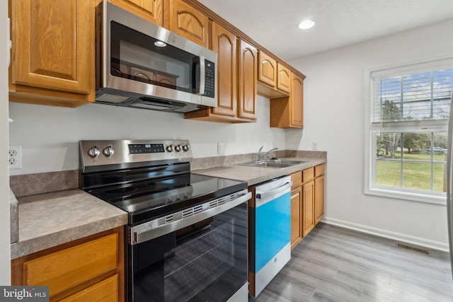 kitchen featuring sink, light wood-type flooring, and appliances with stainless steel finishes