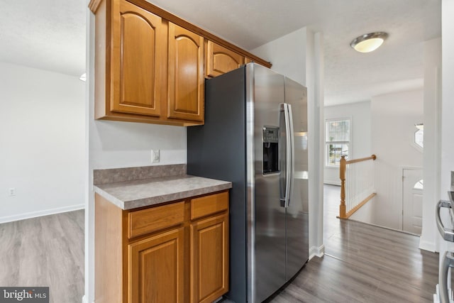 kitchen with stainless steel refrigerator with ice dispenser and light hardwood / wood-style floors