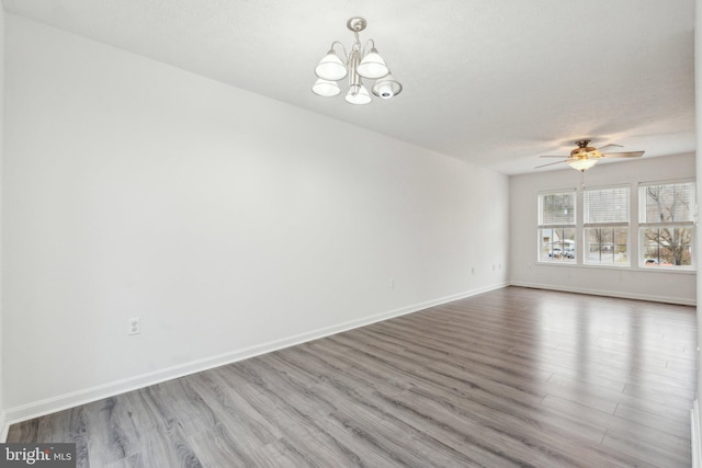 empty room with ceiling fan with notable chandelier, wood-type flooring, and a textured ceiling