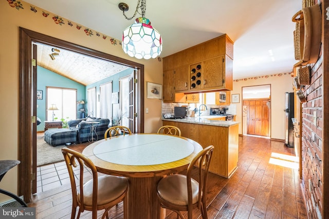 dining area with vaulted ceiling, dark wood-type flooring, and sink