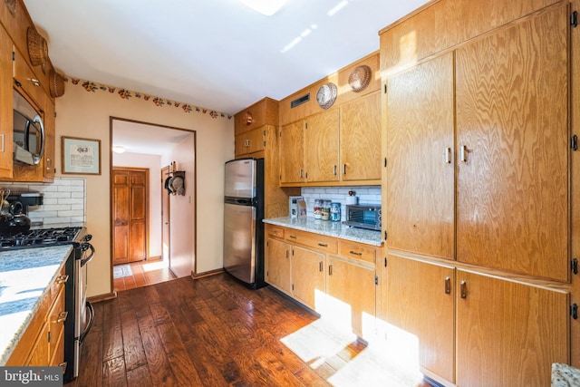 kitchen with tasteful backsplash, appliances with stainless steel finishes, and dark hardwood / wood-style flooring