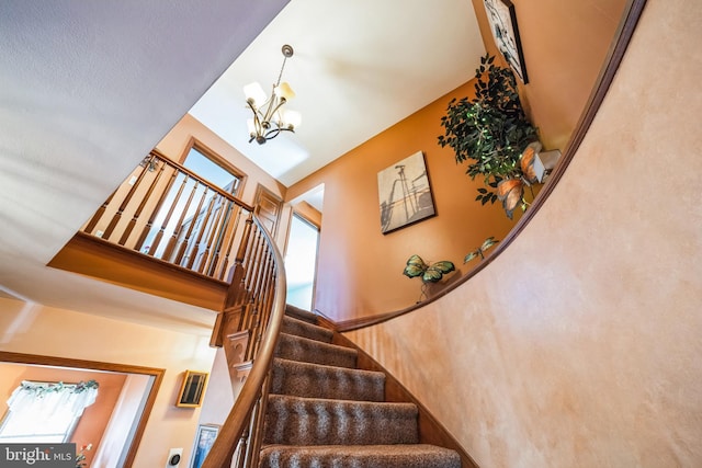 stairway with a high ceiling and an inviting chandelier