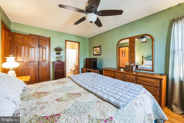 bedroom with connected bathroom, hardwood / wood-style floors, and ceiling fan