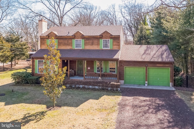 view of property with a garage, covered porch, and a front yard