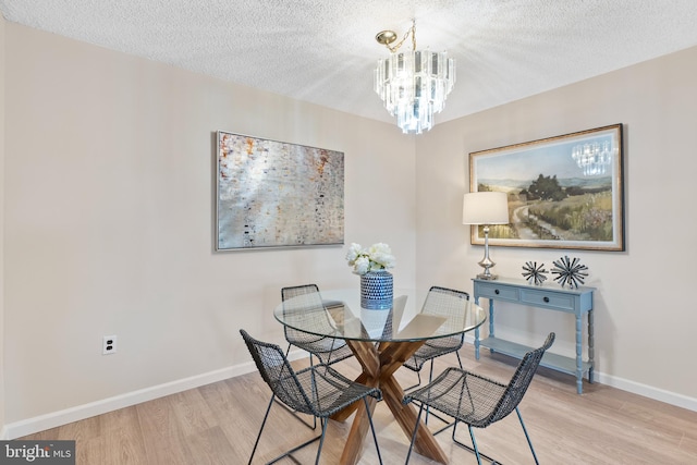 dining space with a textured ceiling, light hardwood / wood-style flooring, and a notable chandelier