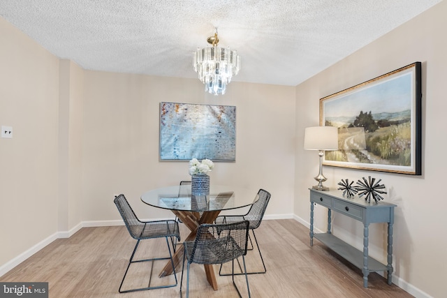 dining room with an inviting chandelier, a textured ceiling, and light wood-type flooring