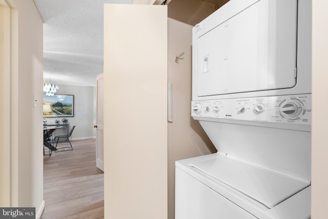 laundry area with light hardwood / wood-style floors, stacked washer and clothes dryer, and a textured ceiling