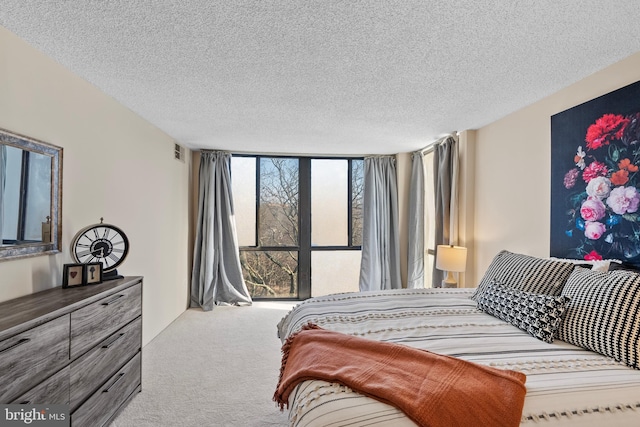 carpeted bedroom featuring a textured ceiling and a wall of windows