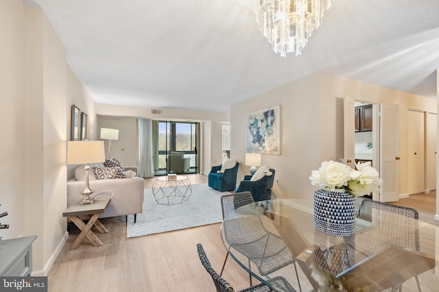 living room featuring an inviting chandelier, wood-type flooring, and a textured ceiling