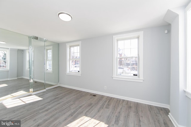 unfurnished bedroom with multiple windows, wood-type flooring, and a closet