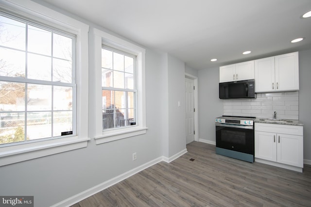 kitchen with electric stove, sink, plenty of natural light, tasteful backsplash, and white cabinets