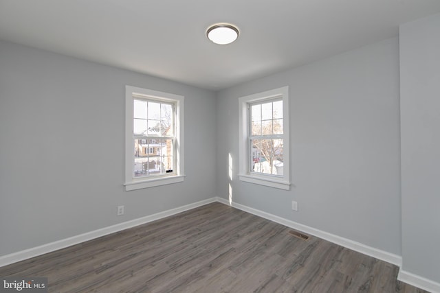 unfurnished room featuring dark wood-type flooring and plenty of natural light