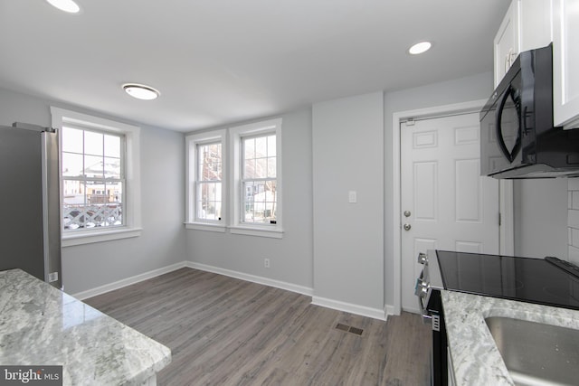 kitchen featuring light stone counters, electric range oven, white cabinetry, and stainless steel fridge